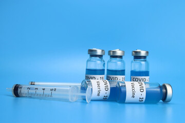 Ampoules of the coronavirus vaccine injection on a blue background. COVID-19 vaccination concept