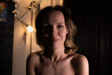 Portrait of a middle aged woman with bare shoulders shirtless in a dark room