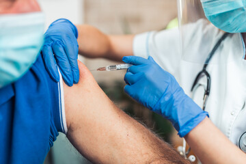 Female doctor vaccinating senior male patient at home. Coronavirus, Covid-19 concept.
