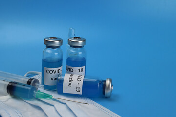 Ampoules of the coronavirus vaccine injection on a blue background. COVID-19 vaccination concept