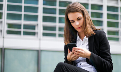 Fototapeta premium Portrait of a young woman talking on the phone sitting on a bench outdoor