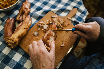 Close-up of men's hands cleaning pork legs with a knife, which are one of the ingredients for the traditional Serbian dish "Pihtije"