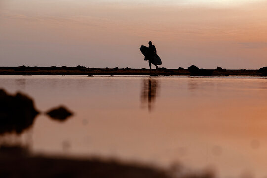 Silhouette of surfer at sunset on the beach