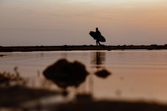Silhouette of surfer at sunset on the beach