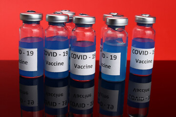 Coronavirus vaccine in ampoules on the mirror table. COVID-19 vaccination concept