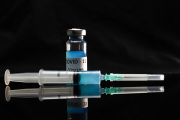 syringe and a coronavirus vaccine on a glass table