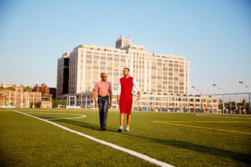 Man and father walking on soccer field during sunny day