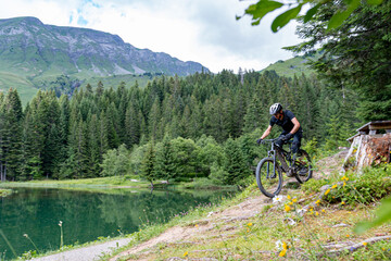Riding his mountain bike near the lake and trees, les portes du soleil, Morzine, France