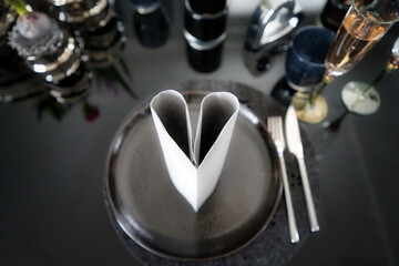 Vornehm gedeckter Tisch mit schwarzem Steinteller, Besteck und Serviette als Herz gefaltet