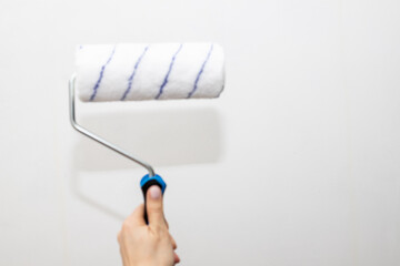 Hand Of Worker With Paint Roller Painting Wall Inside In Apartment Close Up. Repair In House. repair and maintenance concept.Copy space