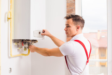 The plumber works with boiler at the kitchen