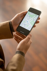 Hands of young man trying to find out street or house on online map of the city