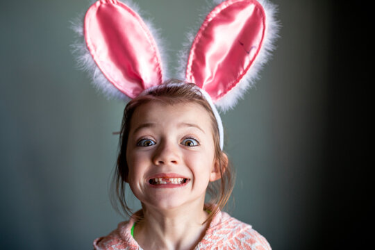 Portrait of playful girl wearing rabbit ears headband while showing gap toothed at home