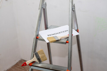 text renovation, black letters on white paper. home improvement, dirty paint ladder, roller, brush...