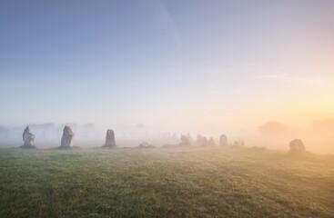 Menhir alignment view at Camaret sur mer in a morning fog at sunrise. Brittany, France. Golden...