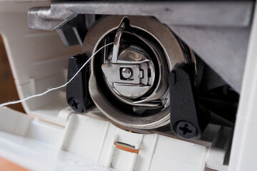 close the metal of the Shuttle device the sewing machine with white thread side view