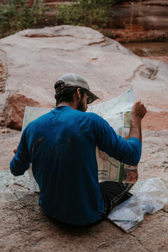 Rear view of man reading map while sitting at Grand Canyon National Park