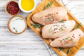 Chicken fillet with herbs and spices on white wooden table. Top view, copy space