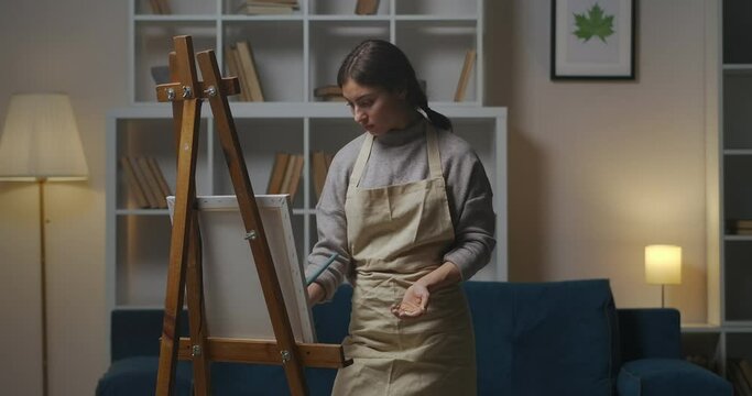 drawing woman in apartment at evening, creative hobby of female artist, working in home studio, medium portrait in living room