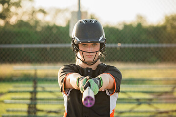 Portrait of softball player holding baseball bat while standing at playing field