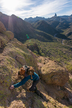 High angle view of man carrying German Shepherd in backpack while climbing mountain against sky