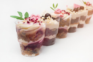 Sweet small homemade trifle dessert with custard, chocolate, nuts and fruits and decorations and cream cheese.