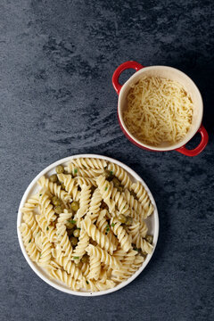Overhead view of pasta served by grated cheddar cheese in bowls on table