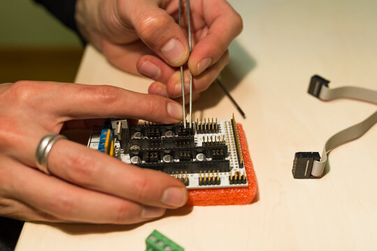 Cropped hands of male engineer repairing mother board on table in office