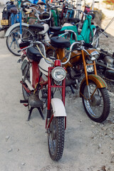 group of old motorcycles stands on the street in the summer on the rocks