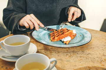 Close-up. Woman eats Belgian waffles for breakfast
