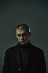Brutal angry guy security or criminal in black costume frowning, studio male portrait with copy...