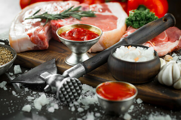 Raw meat with spices in a composition with kitchen accessories.
