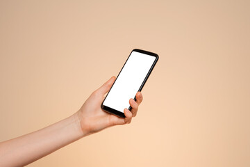 Smartphone with a blank screen in a woman's hand on a orange background.