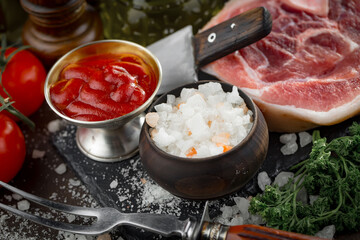 Raw meat with spices in a composition with kitchen accessories.