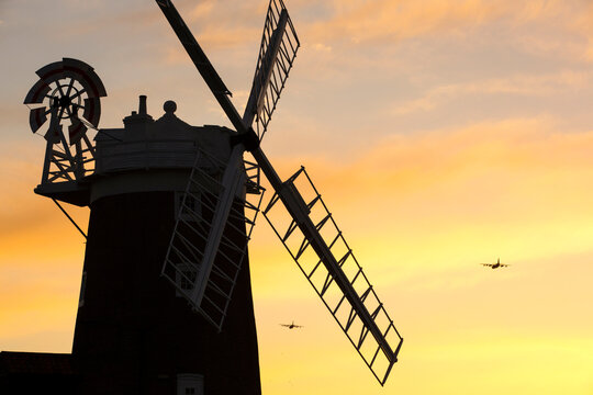 A windmill at Cley Next the Sea, North Norfolk, UK, at sunset, with RAF planes flying past.