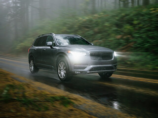 SUV automobile driving through foggy and rainy forest road