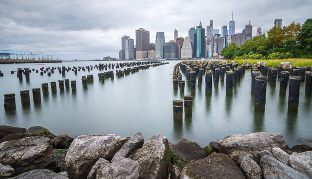 Manhattan financial district on a beautiful summer morning. Long exposure photo of the financial district of Manhattan on a cloudy summer morning, on the old pier - image