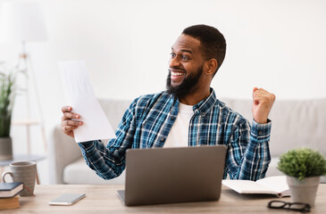 Joyful Black Businessman Shaking Fists Holding Papers In Office