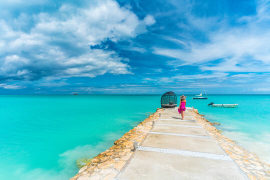 Woman walking on jetty towards a luxury gazebo over Caribbean Sea