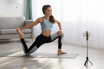 Obraz premium Positive sporty lady stretching in front of smartphone