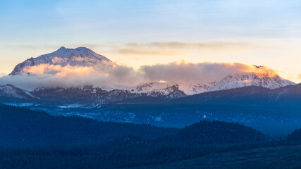 Fototapeta na wymiar This image captures Mount Lassen and Chaos Crags semi-cloaked in low clouds during the golden hour in January as seen from the Hat Creek Rim in western Lassen County.