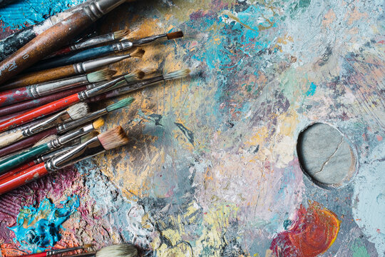 used and painted brushes on a palette of colours