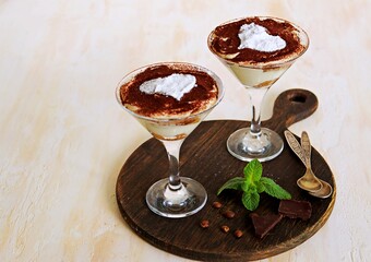 Tiramisu, dessert with biscuit cookies and mascarpone cream in triangular glasses on a light concrete background. Dessert recipes without baking. Desserts in glasses.