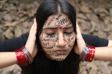 A southeast Asian brown woman protesting gender based violence by writing anti violence against women and girls messages all over her face