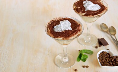 Tiramisu, dessert with biscuit cookies and mascarpone cream in triangular glasses on a light concrete background. Dessert recipes without baking. Desserts in glasses.