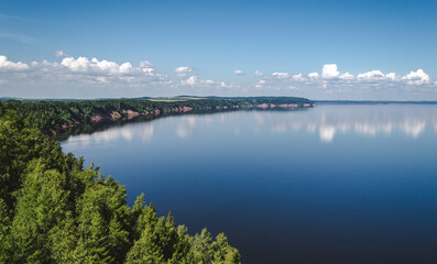 Peaceful landscape of blue lake with clouds, wooded shoreline