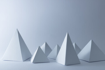 white 3d handmade pyramids on white background, selective focus