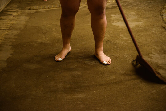 Low section of wrestler sweeping field with broom in sumo beya