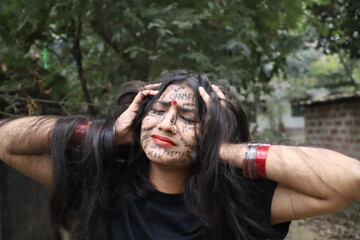 Fototapeta na wymiar A southeast Asian brown woman protesting gender based violence by writing anti violence against women and girls messages all over her face and looking angry and sad