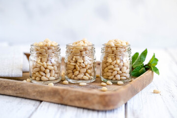 Cedar nuts in glass bank on rustic wooden background. Peeled pine nuts